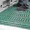dunkelgrüne Bodenroste aus Kunststoff mit Auffahrkeilen, auf denen ein Arbeiter steht, vor einer grauen Werkzeugmaschine